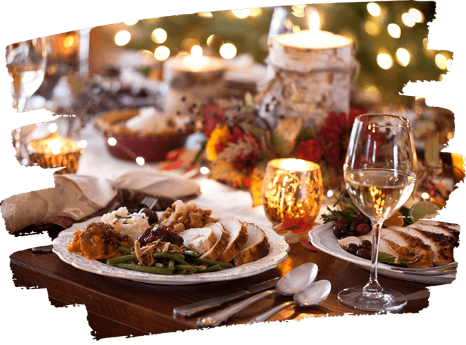 Festive dinner table with plates of turkey, green beans, stuffing, and a glass of white wine, surrounded by lit candles and holiday decorations.